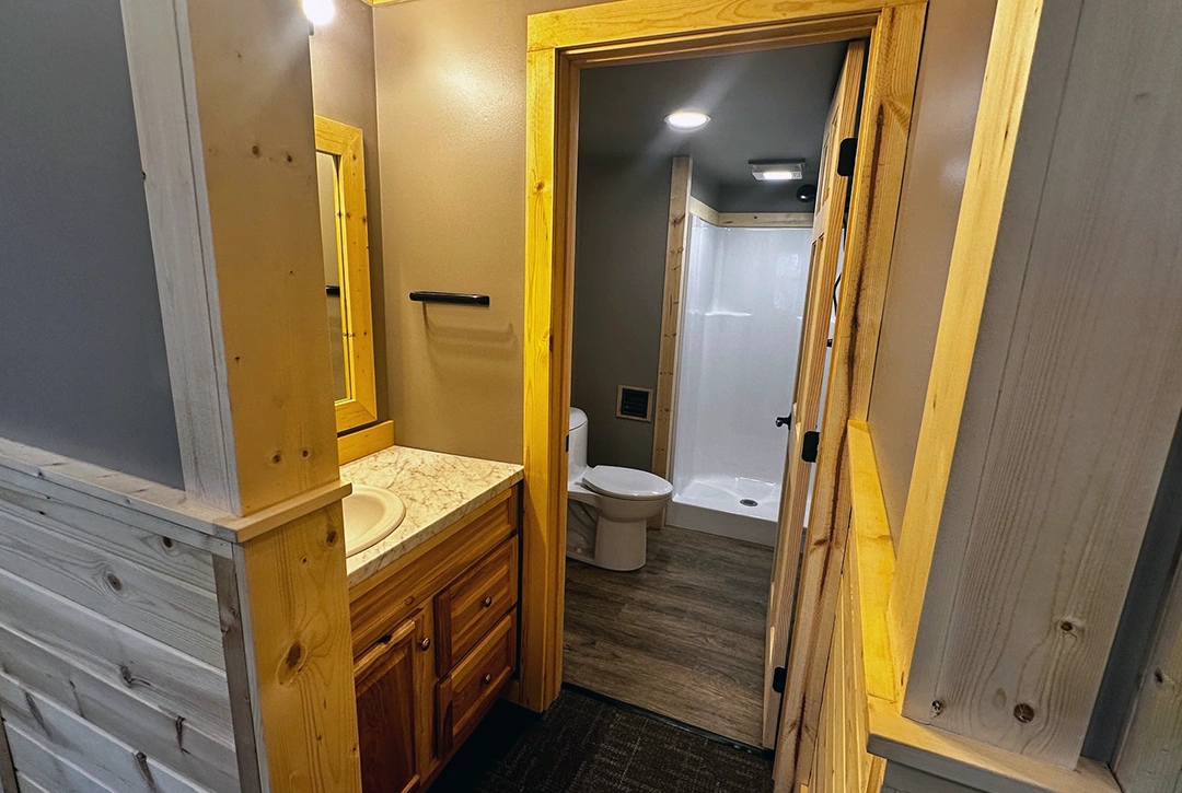 Compact campground bathroom with walk-in shower, toilet, and vanity featuring efficient space utilization and modern fixtures for guest comfort at Sky Ranch Campground