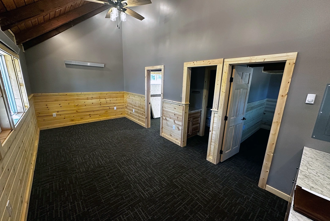 Multi-room campground lodge with exposed ceiling beams, wood paneling, and commercial-grade carpet flooring demonstrating True North Construction's expertise in recreational facility construction