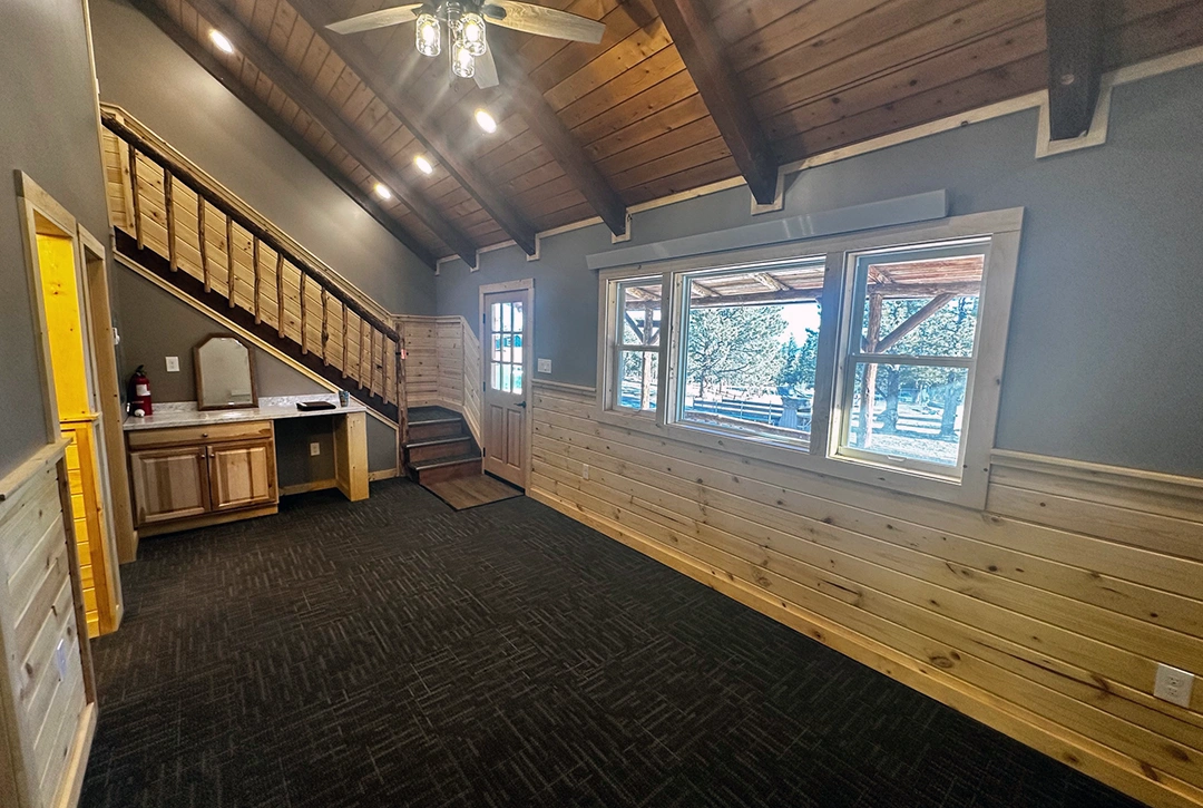 Spacious campground lodge interior with exposed wood beam ceiling, rustic wood wainscoting, and large windows providing natural light - commercial construction by True North Construction Company